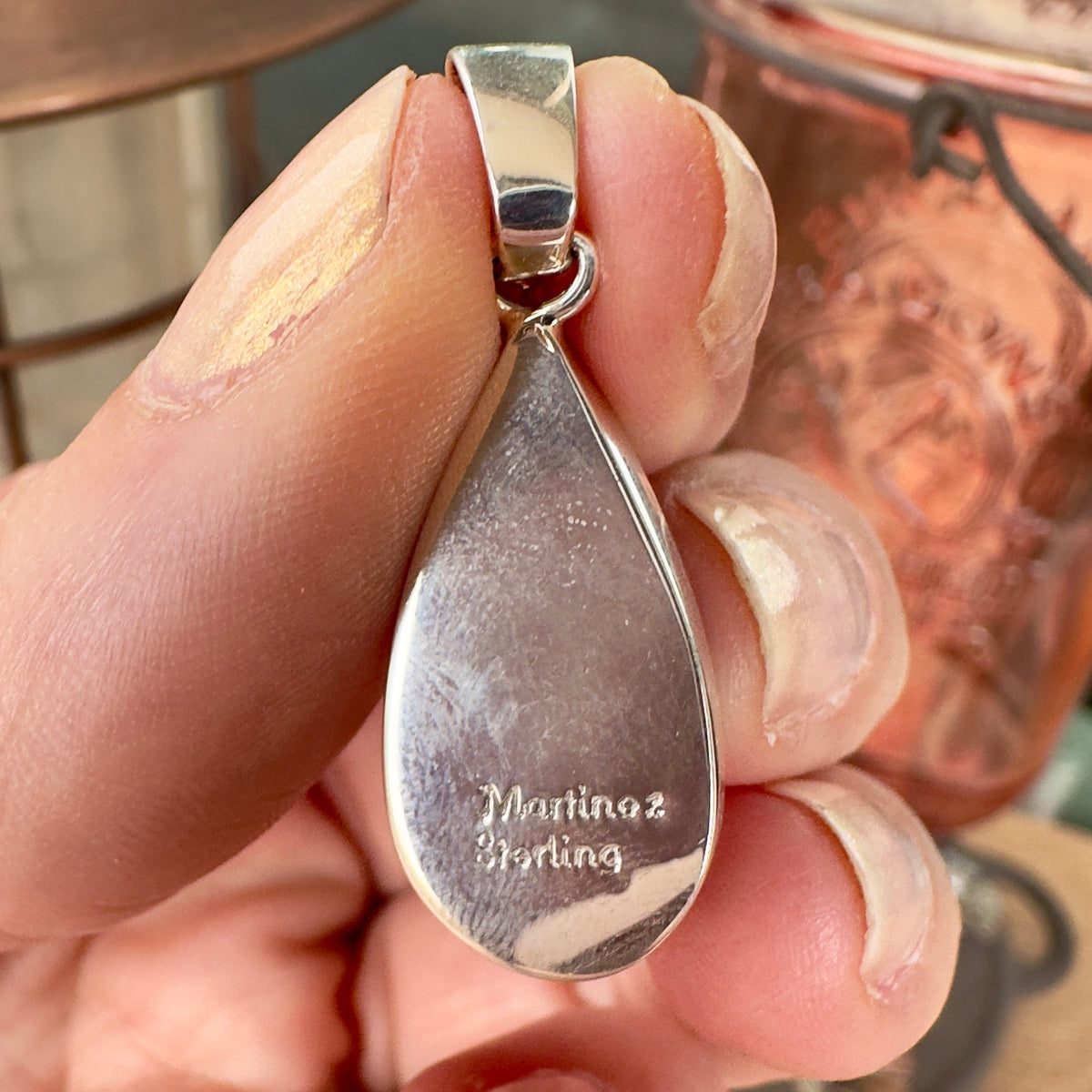 Wildflower Artisans sterling silver pendant back showing Martinez hallmark and teardrop shape held in hand