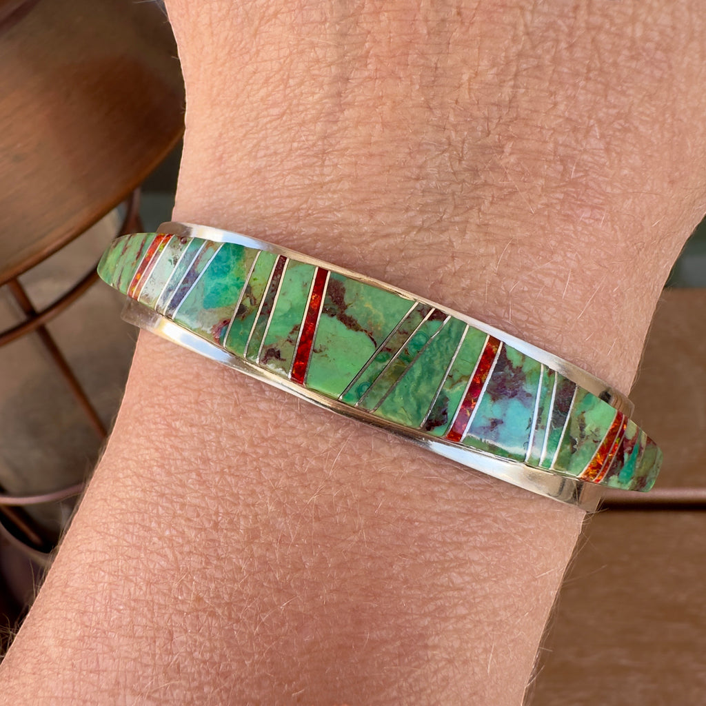 Wildflower Artisans sterling silver cuff featuring Sonoran Mountain turquoise and red opal channel inlay on a wrist.