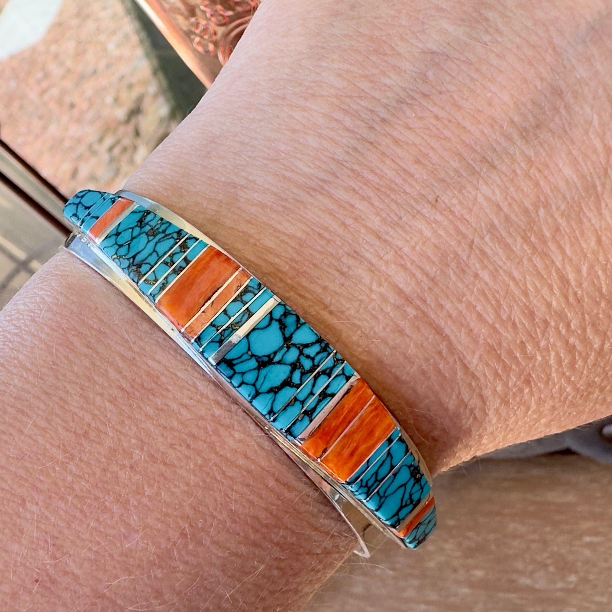Wildflower Artisans sterling silver cuff bangle with hand-inlaid turquoise and orange spiny oyster on a wrist