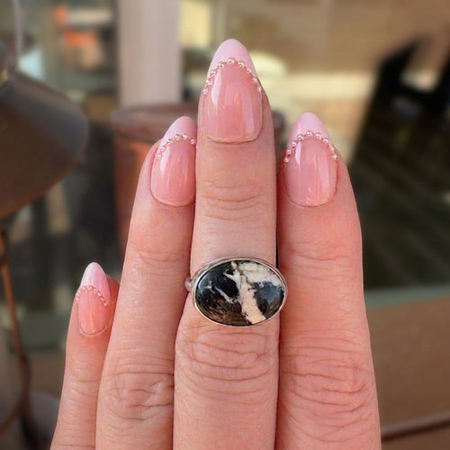 Wildflower Artisans sterling silver ring featuring a natural White Buffalo stone with charcoal veining on a finger.