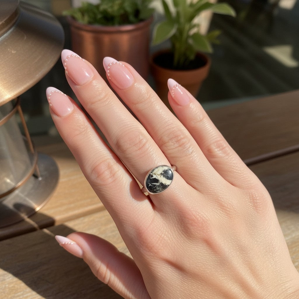 Wildflower Artisans sterling silver ring featuring a natural White Buffalo stone with charcoal veining on a hand.