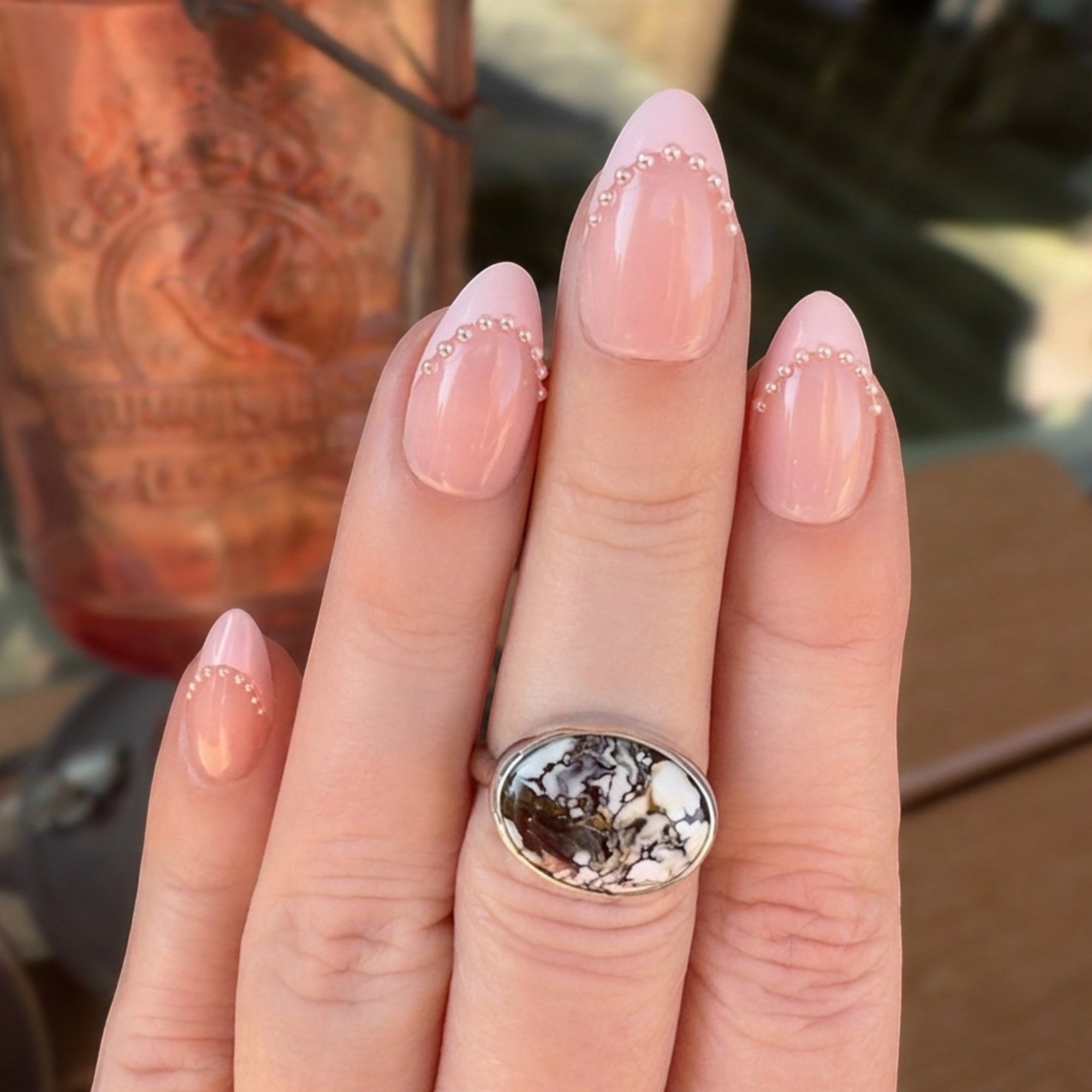 Wildflower Artisans sterling silver ring featuring an oval Wild Horse stone with rust and cream patterns on a hand.