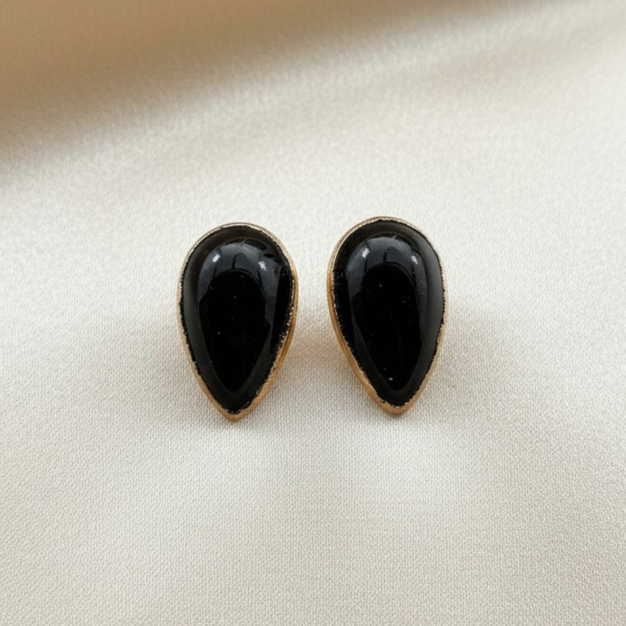 Wildflower black onyx teardrop stud earrings in 24K gold bezel. Pear-shaped polished onyx.