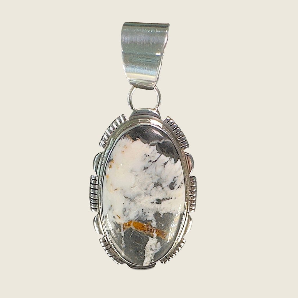 White buffalo pendant necklace in Navajo sterling silver by Leslie Yazzie, shown on a bone linen background